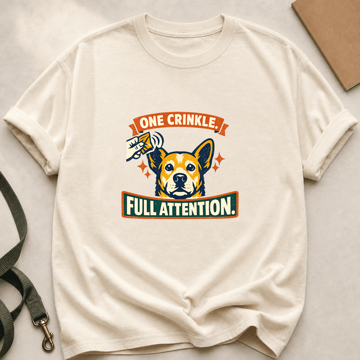 Ivory Comfort Colors T-shirt printed with One Crinkle, Full Attention around an alert dog and treat-packet sound waves.