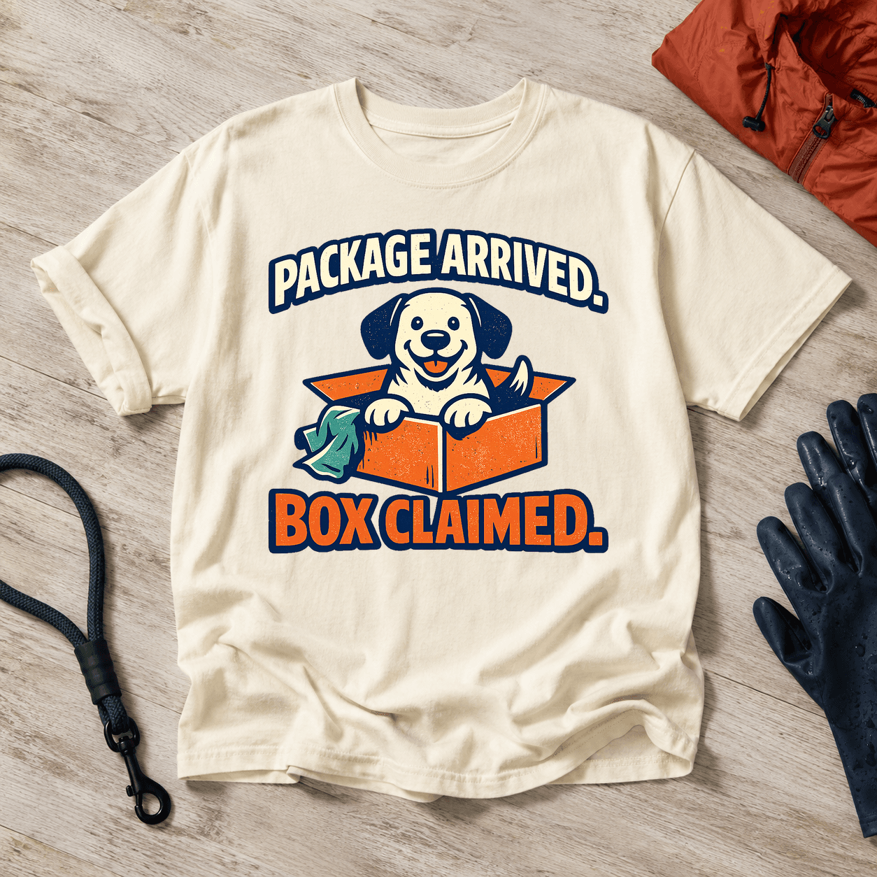 Ivory Comfort Colors T-shirt printed with Package Arrived. Box Claimed. and a happy dog sitting in an orange parcel box.